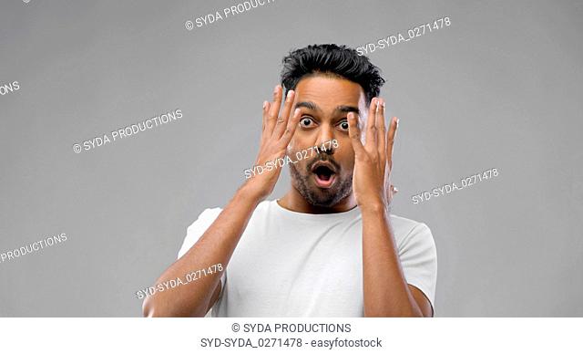 shocked indian man over grey background
