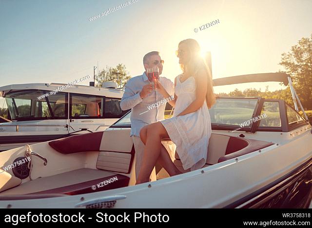 Couple in a river boat or yacht toasting with sparkling wine, backlit scene