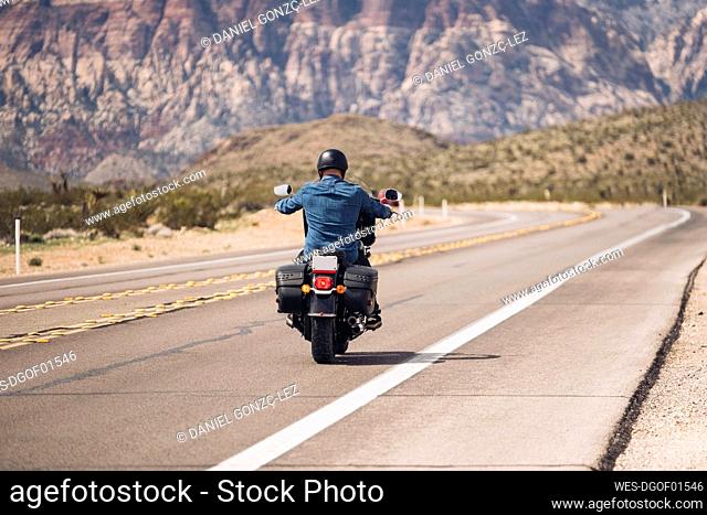 Man riding motorcycle on desert road, Nevada, USA