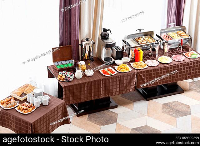 Breakfast at the hotel. Buffet Table with dishware waiting for guests. hot meals, vegetables, fruits, meats, cheeses. Coffee machine