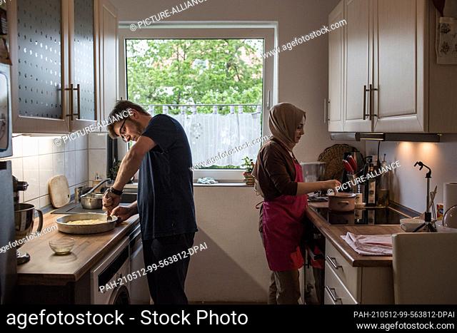 PRODUCTION - 10 May 2021, North Rhine-Westphalia, Minden: Hatice Bahadir (r) and Abdurrahman Bahadir prepare the iftar together in their kitchen