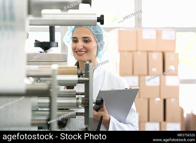 Female manufacturing supervisor looking worried while checking equipment and production during quality control in the interior of a cosmetics factory