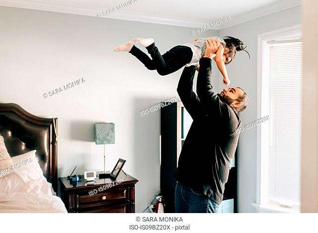 Girl being held up by father in bedroom