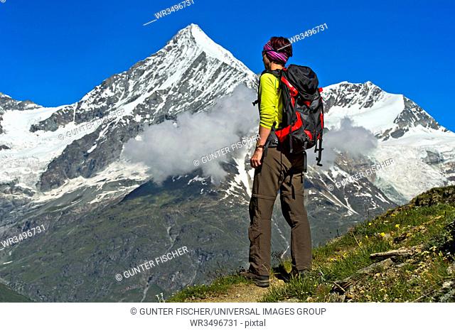 Woman with backpack looking at the Weisshorn peak above the Mattertal valley, Taschalp, Valais, Switzerland