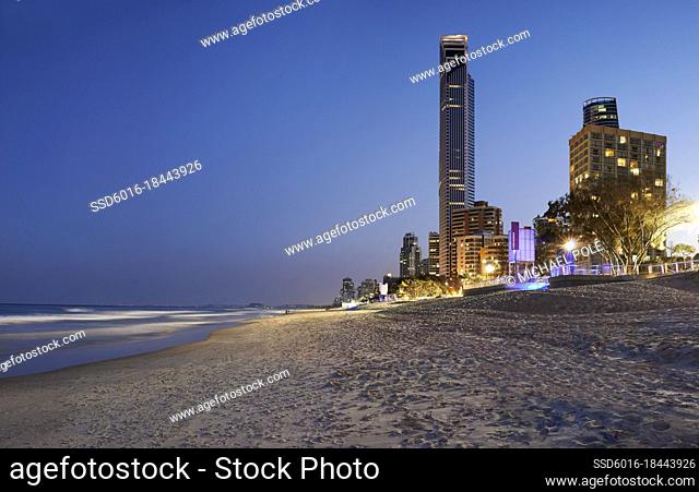 View looking down beach at Coastling from Surfers Paradise to Coolangatta and lights on in buildings in the early evening