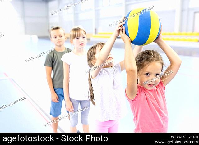 Girl passing ball to friend standing in line at school sports court