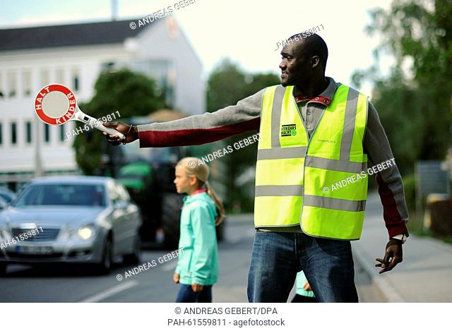Asylum seeker Souleyman Cisse practices his new tasks as a crossing guard at a school in Ebersberg, Germany, 8 September 2015
