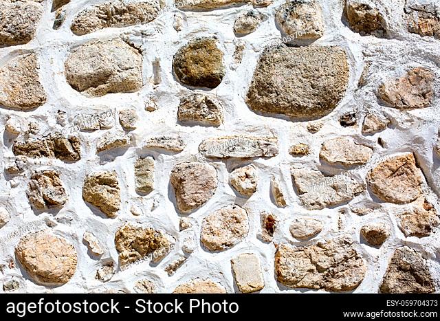 Background with traditional Bulgarian house wall with stones and white paint between them
