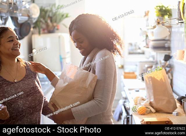 Mother and daughter unloading groceries in kitchen