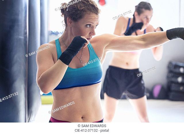 Determined, tough female boxer shadowboxing in gym