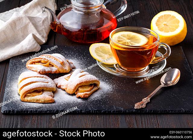 Cottage cheese cookies with apple on plate with tea on dark wooden table