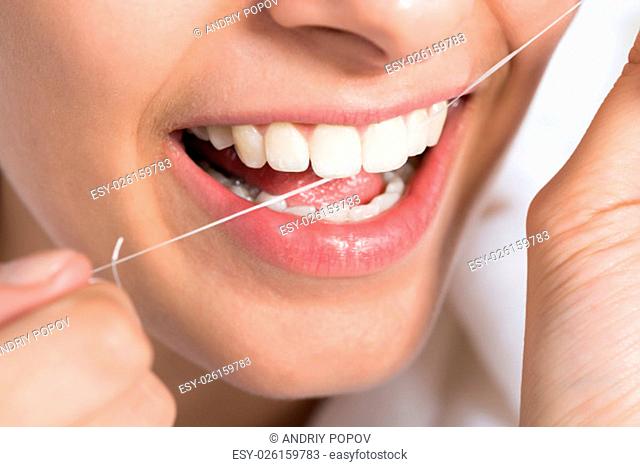 Closeup of young woman flossing teeth at home