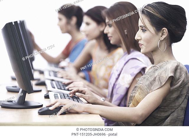 Side profile of four businesswomen in front of computers
