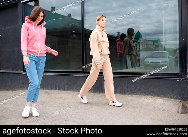 Two girls walking on the city street. Young woman outdoors