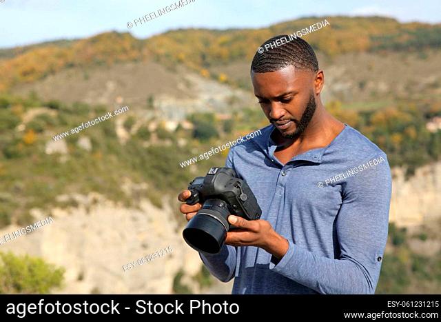 Man with black skin checking photos on dslr camera
