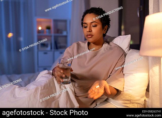 woman with medicine and water in bed at night