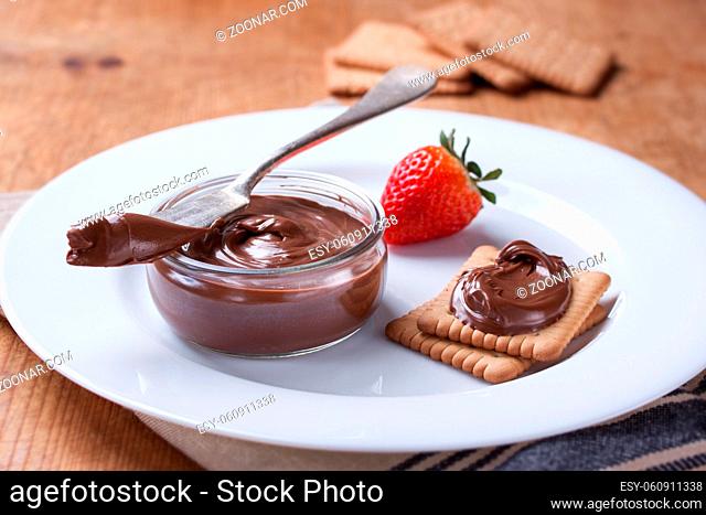 Chocolate sweet melting nougat cream on cookies with strawberries on a white plate. Closeup