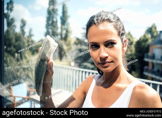 Woman cleaning glass window on sunny day