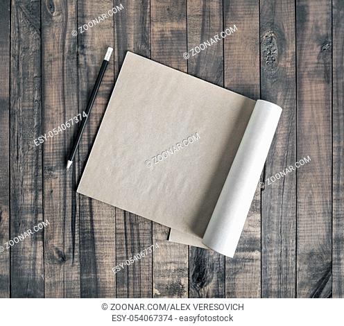Blank brochure or notepad of kraft paper and pencil on wood background. Flat lay