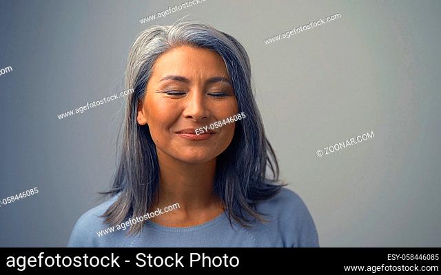 Charming Asian Lady Is Posing With Closed Eyes. She Is Dreaming About Something Pleasant.The Lady Looks Happy.Toned Background