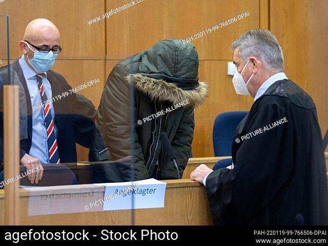 19 January 2022, Hessen, Frankfurt/Main: A Syrian-born doctor (M) stands in the dock of the Higher Regional Court in Frankfurt between his defense lawyers...