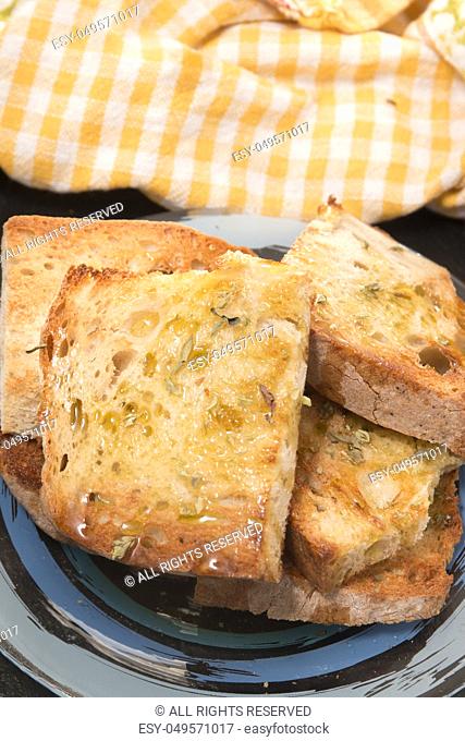 Traditional Portuguese bread toasted with virgin olive oil and oregano herbs on a shale stone