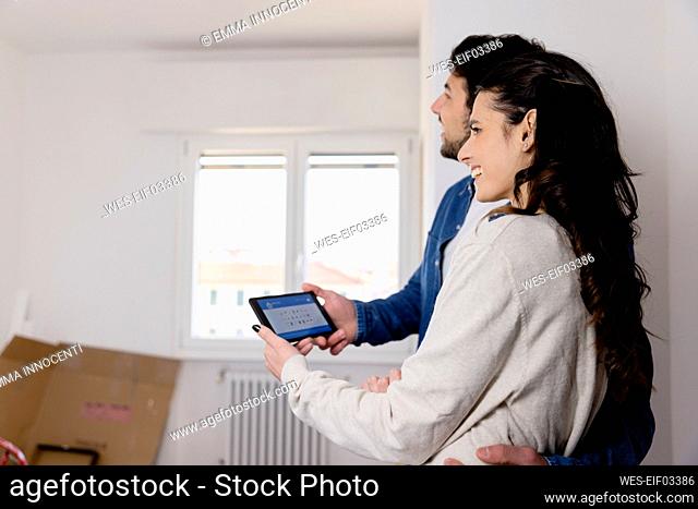 Young couple holding tablet PC at new home