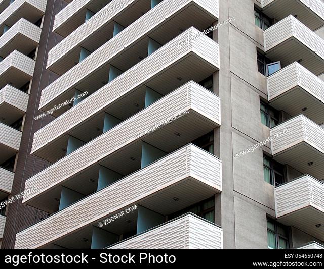 modern tall white concrete apartment block with geometric angular balconies