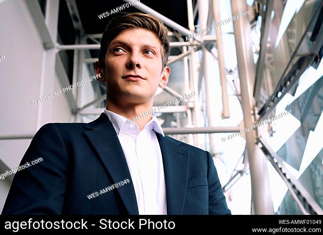Thoughtful young businessman standing in front of scaffolding