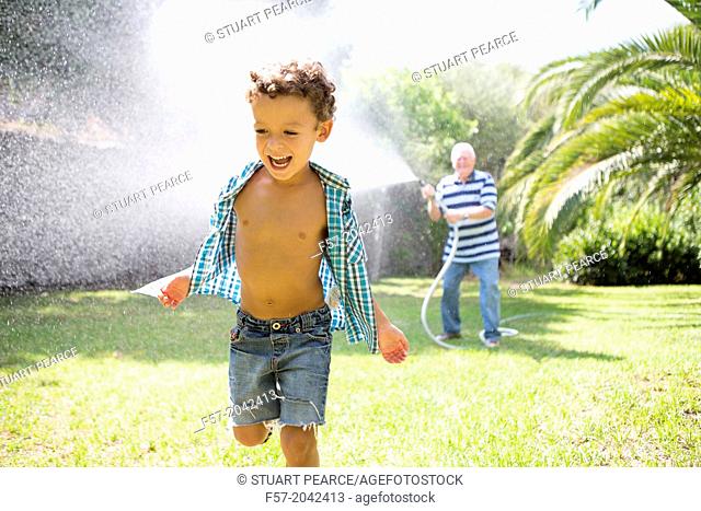 Young boy playing with his grandfather in the garden