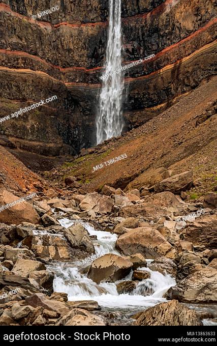Hengifoss waterfall in East Iceland. Hengifoss is the third highest waterfall in Iceland and is surrounded by basaltic strata with red layers of clay between...