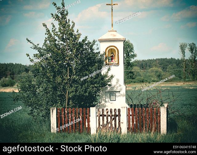 Old wayside shrine in polish countryside stand amid fields of rye