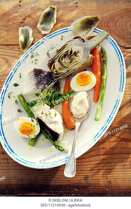 Provencal appetiser featuring artichokes, poached cod, vegetables, eggs and aioli
