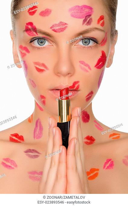 Beautiful woman with kisses on face holding lipstick