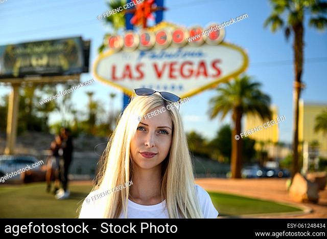 Portrait of a gorgeous blonde woman on the Las Vegas Strip standing under the world famous Welcome To Fabulous Las Vegas Nevada sign, USA