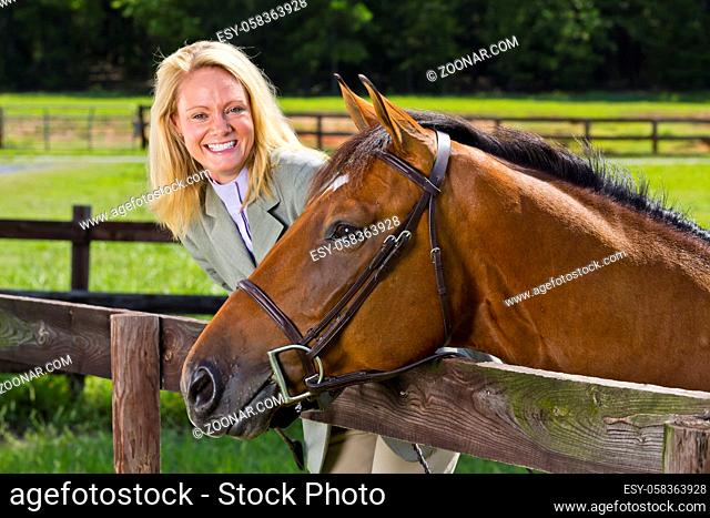 A blonde equestrian model poses outdoors before a horse show