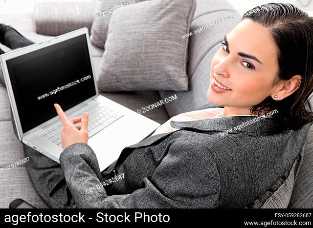 Young businesswoman sitting on sofa, working with laptop computer. Isolated on white background, overhead view