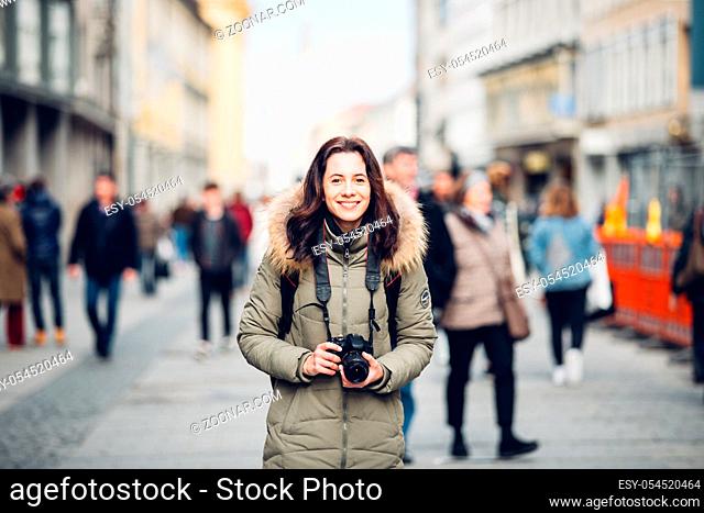 portrait Beautiful young tourist woman stands in the background of a crowd of people on a central street in Munich in Germany in winter