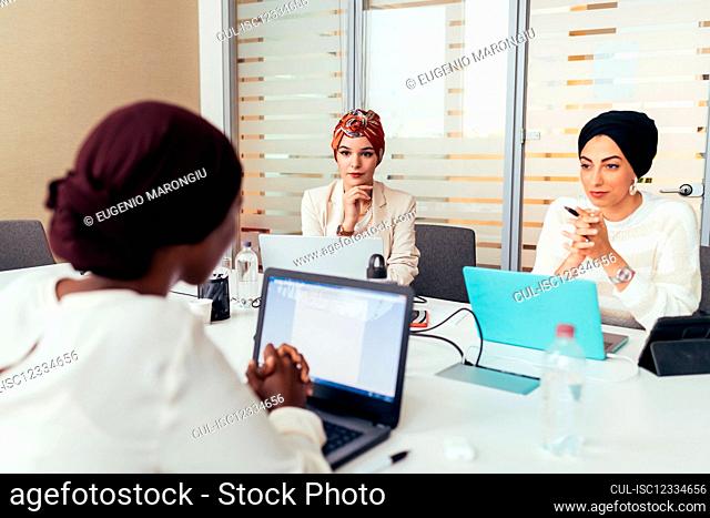 Three female colleagues working at shared desk