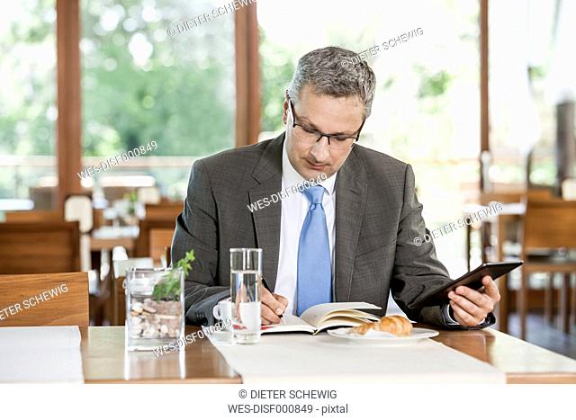 Businessman in restaurant writing in notebook