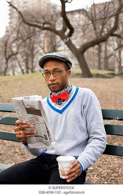 Man sitting on a park bench with a newspaper, Central Park, Manhattan, New York City, New York State, USA