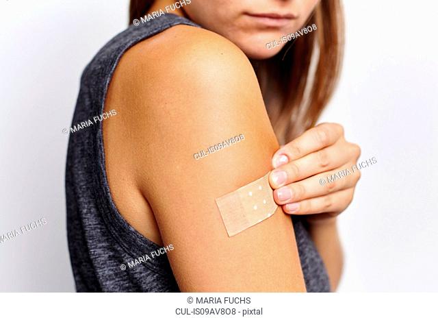 Woman applying plaster on right arm