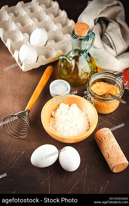 Ingredients for cooking pirok or cookies - flour in a wooden bowl, eggs, butter, cinnamon, anise and a small decorative wooden rolling pin