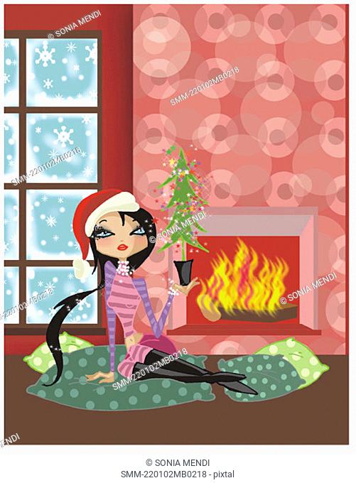 Woman sitting by the fire with a little Christmas tree