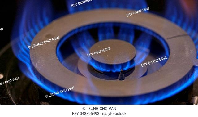 Stove burner igniting into a blue cooking flame