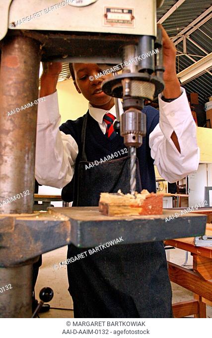 School boy using pillar drill in woodwork classroom, St Mark's School, Mbabane, Hhohho, Kingdom of Swaziland