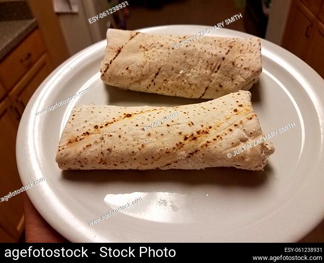 two frozen burritos on a white plate in the kitchen