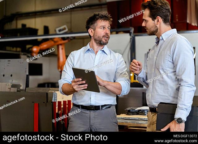 Business people having discussion while using digital tablet at factory