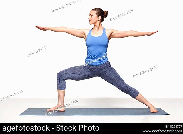 Beautiful sporty fit yogini woman practices yoga asana Virabhadrasana 2, warrior pose 2