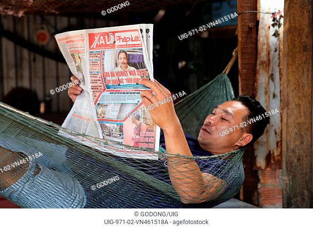 Man reading newspaper in a Hammock